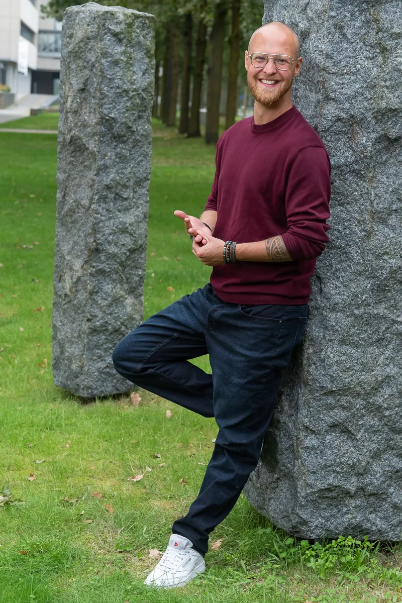 Merlijn Linschooten, fractional CMO for deep-tech startups, leaning against a granite column at High Tech Campus Eindhoven